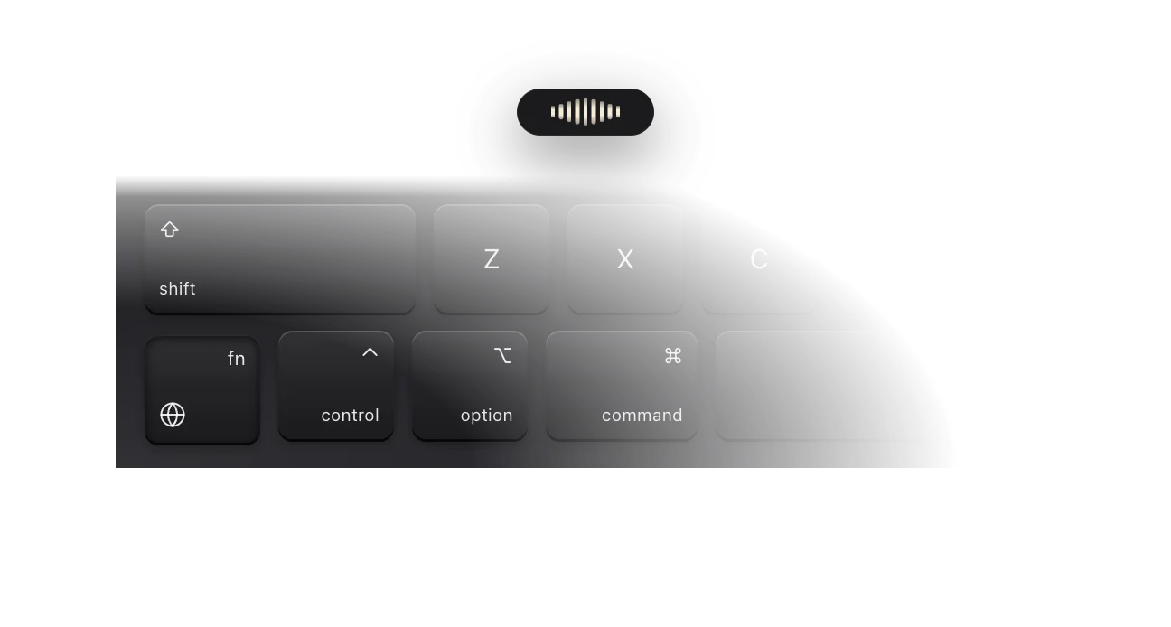 The dictation pill listening above a keyboard corner with the Globe key held.